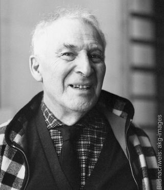 A black-and-white portrait of the smiling painter Marc Chagall wearing a patterned jacket, shirt and tie.